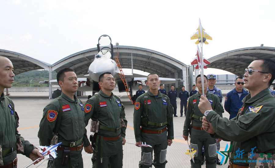 ↑舰载航空兵某部司令员戴明盟向飞行员演示空中飞行注意事项。